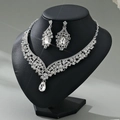 Detailed view of silver luxury rhinestone necklace and earrings on a black neck display - Silver