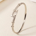 Silver nail bangle with cubic zirconia pavé setting on a cream leather surface - Classic Nail Style (BS-J5507S) / Silver