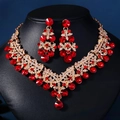 Detailansicht von Brautschmuck-Set mit roten Kristallen und Strasssteinen auf schwarzem Samt - Gold Roter Zirkonia