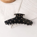 Glossy black acrylic hair claw clip with golden bead rivets on white linen texture - Black