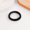 Élastique à cheveux noir sans couture sur une assiette en céramique et fond en bois - Noir