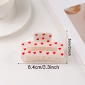 Beige hair claw clip with red heart patterns shown in a lifestyle scene with dimensions - 8.4cm / White