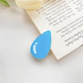 Blauer Acryl-Haarclip in Wassertropfenform auf einem Buch mit weißen Details - Wassertropfen