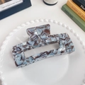 Blue and white marble acetate hair claw clip with rectangular cutout on a ceramic plate - Gemstone Grey