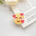 Niedliche gelbe Emoji-Haarklammer mit Herzaugen auf modernem Zeitschriftenhintergrund - Herz