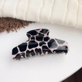 Pink and black animal print hair claw clip in a glossy finish for elegant styling - Black Cow Print