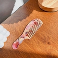 Peine de dientes anchos en acetato con patrón de mármol rosa y beige en mesa de madera - Púrpura Uva