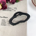 Minimalistische mattschwarze Haarklammer in Wellenform auf beigem Vintage-Hintergrund - Wolke Schwarz 11cm