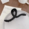 Große Haarklammer in Matt-Schwarz mit gedrehtem Design auf Keramikteller - Welle Schwarz 13CM