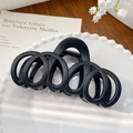 Mattschwarze hohle Haarklammer für Damen auf einem weißen dekorativen Porzellanteller - Mehrring Schwarz 12.5CM