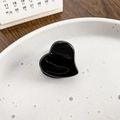 Glossy black heart-shaped acetate hair claw clip on a white ceramic plate - Black