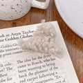 Mini pince à cheveux en peluche crème sur une table en bois au style cocooning - Café au Lait