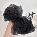 Pinza para el pelo con lazo grande negro de tela seersucker con textura en la mano - Negro