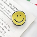 Κίτρινη βάση κινητού με σχέδιο smiley και γυαλιστερό φινίρισμα πάνω σε ανοιχτό βιβλίο - Κίτρινο της Μουστάρδας 2CM