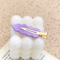 Matte purple wavy acrylic hair clip with gold metal clip on white candle decor - Purple