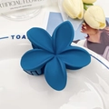 Matte navy blue frangipani flower hair claw clip displayed on a decorative ceramic plate - Blue