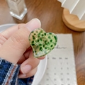 Pince à cheveux cœur en acétate vert à motif floral présentée dans une scène de vie - Vert Moucheté