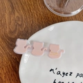 Pink cat-shaped hair clip with French logo on a wooden table and ceramic plate - Pink Cat