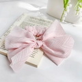 Eleganter Haargummi mit rosa-weißem Fischgrätmuster und großer Schleife auf einer Modezeitschrift - Rosa
