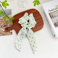 Elegante coletero blanco con lunares verdes y flores amarillas sobre madera - Cinta Bicolor