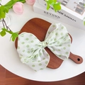 Oversized light green polka dot bow hair clip on a wooden tray with floral decor - Gold Piece Bow