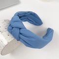 Minimalist light blue fabric knotted headband with soft texture shown on a ceramic cup - Blue