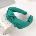 Chic knotted wide headband in vibrant lime green textured fabric on a white cup - Green