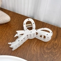 White butterfly hair claw clip with black polka dots on a wooden surface - White Ribbon Style