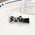Barrette à cheveux nœud noir et blanc au fini poli posée sur une plaque en céramique - Nœud Croisé Noir