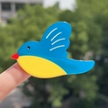 Fermaglio per capelli a forma di uccello blu in acetato, tenuto sulla punta del dito - Uccello Blu