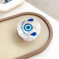 Round blue Evil Eye hair claw clip with white marble texture finish on beige tray - Evil Eye Type 2