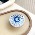Blue Evil Eye round phone grip with marble texture acrylic finish on beige display tray - Eye 4