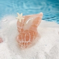 Pinza de pelo con forma de caracola rosa y textura de mármol sobre arena de playa - Naranja