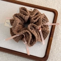 Vue détaillée d'un chouchou en tricot marron avec des rubans roses et des petits nœuds - Marron
