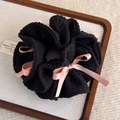 Dettaglio di scrunchie plissettato nero con fiocchi di raso rosa su vassoio espositivo - Nero