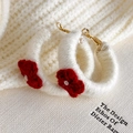 Dettaglio di orecchini a cerchio in lana color crema con fiore rosso all'uncinetto - Bianco