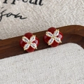 Dettaglio macro di orecchini a fiori in smalto rosso e zirconi su legno - Stile Floreale Borgogna