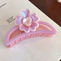 Gros plan sur une pince à cheveux fleur rose nacré sur un fond de page de livre élégant - Croissant Violet Irisé (27820E)