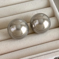 Close-up of metallic silver mirror sphere earrings displayed on beige velvet jewelry box tray - Silver Gray