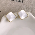 Close-up of minimalist square earrings with white enamel finish and gold edges on a ceramic plate - Irregular Wavy White Style (27861A) / White