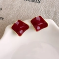 Detailed close-up of dark red enamel geometric earrings with gold-plated edges on a plate - Irregular Wavy Red Style (27861B) / Red