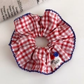 Close-up of red and white checkered scrunchie with blue crochet edge and Happy Peach label - Red White Checkered Button Decor Style (27215C)