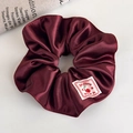 Detailed close-up of a burgundy satin scrunchie featuring a Sweet Cherry fabric label - Wine Red Cherry Label Satin Style (27837A)