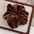 Detail van donkerbruine fluwelen scrunchie met beige bies op houten presentatieblad - koffiekleur