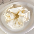 Detalle macro de coletero de satén crema en plato blanco con decoración de papel artístico - Blanco