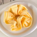 Vista detallada de un coletero de satén amarillo con volantes sobre un plato cerámico - Amarillo