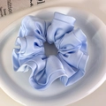 Detalle de coletero de satén azul claro con textura plisada sobre un plato de cerámica - Azul