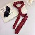 Détail d'une cravate en cuir PU bordeaux avec lunettes sur un livre ouvert - Rouge (27909A)