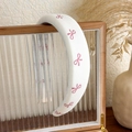 Dettaglio di cerchietto imbottito bianco con piccoli fiocchi rosa su vetro - Fiocco Stampato Rosa