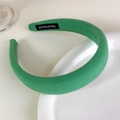 Detailed close-up of emerald green fabric headband with handmade tag on white ceramic - Spring Bud Green